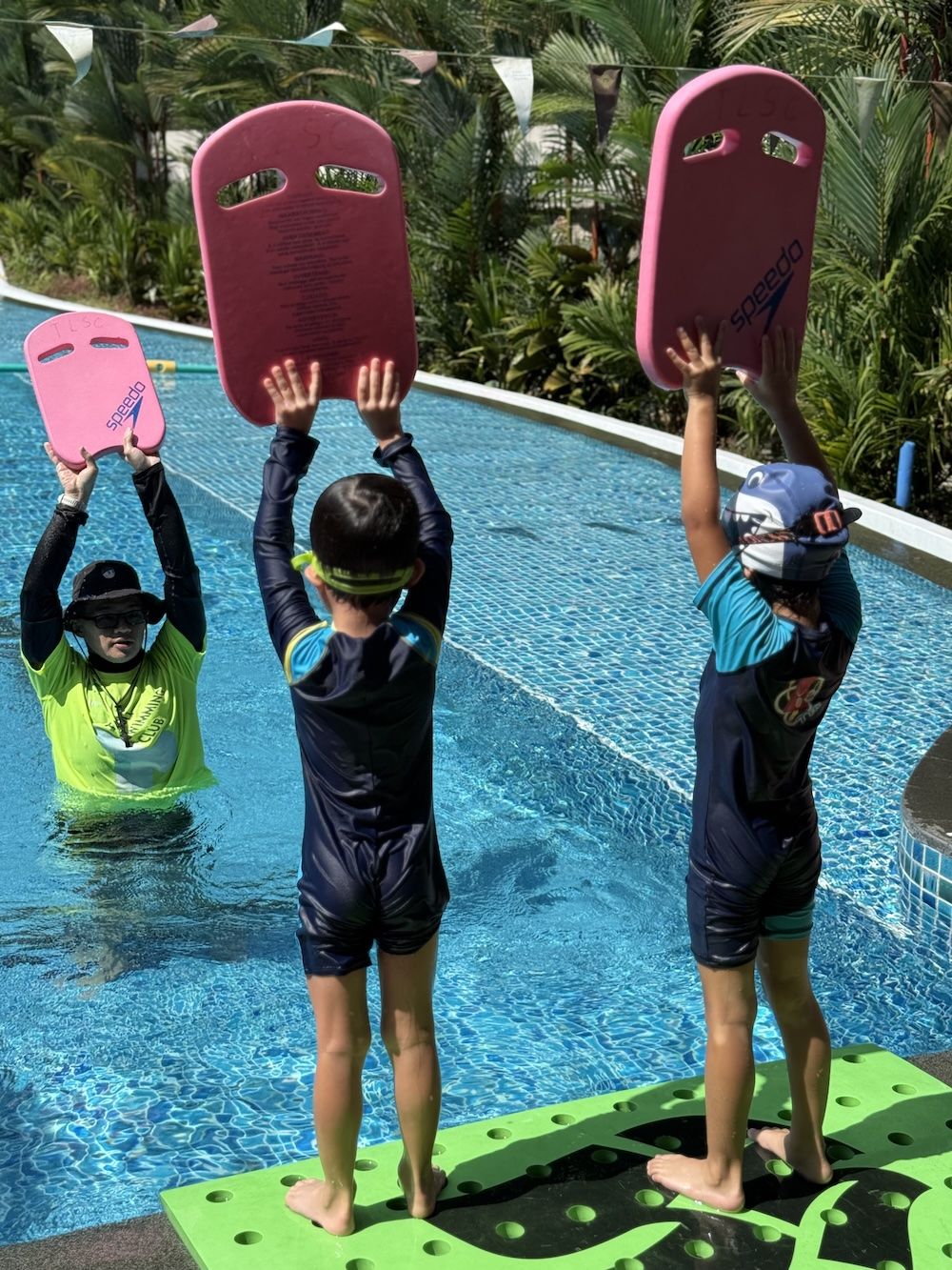 Young children holding kickboards at the pool